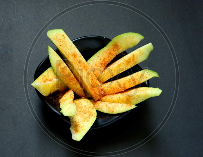 Raw Mango Slices With Salt And Chilli Powder On Isolated Black Background.