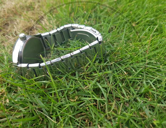 Women Close up Metal colour Watch on the ground in the grass