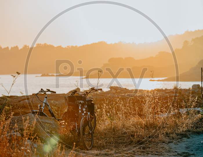 An Horizontal Shot Of Two Vintage Bikes At The Beach During The Sunset