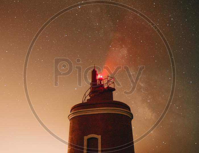 An Horizontal Shot Of A Lighthouse During The Night With The Milky Way Behind It