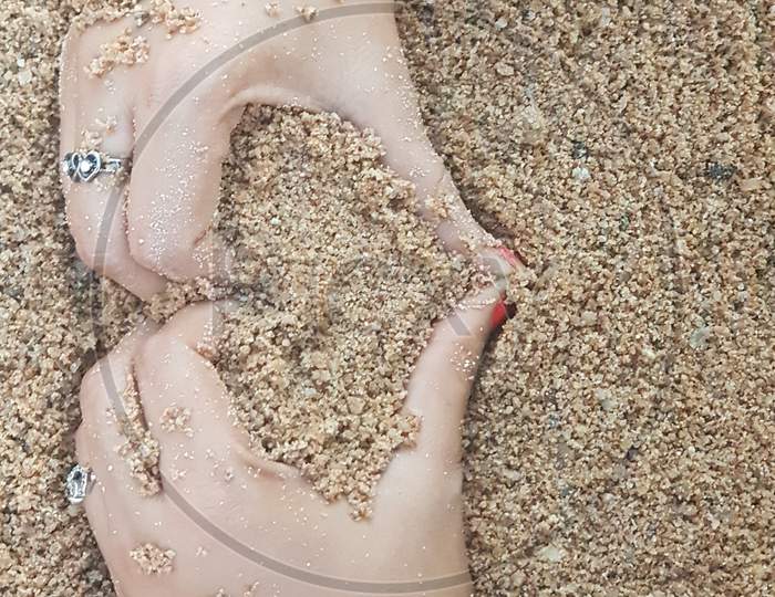 igure of sand in the shape of a heart with hands of a woman