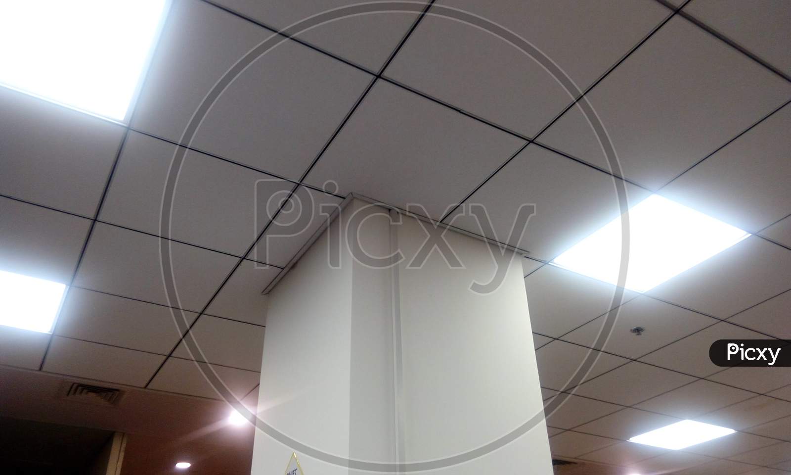 Image Of Office Building False Ceiling Of Calcium Silicate Suspended Grid False Ceiling With 60 X 60 Cm Grid Lighting Around The White Emulsion Painted Column Structure With Necessary Cut Pieces Of