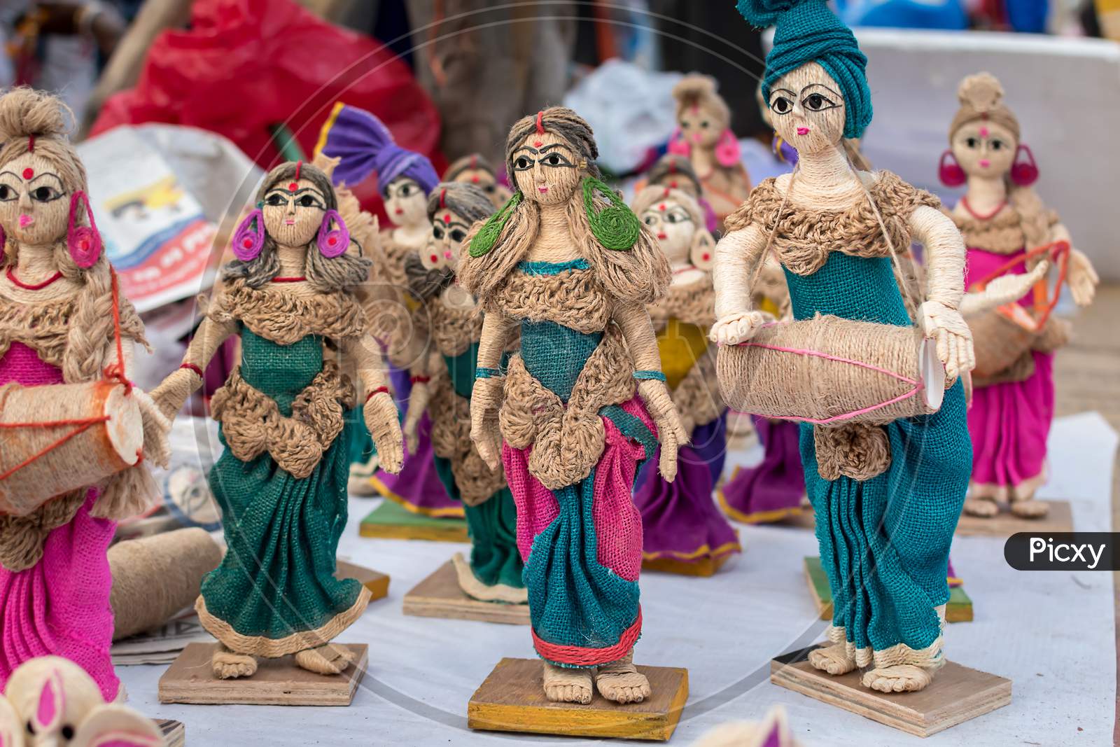 Handmade Puppet Models Of Musicians And Dancers With Traditional Costumes Made Of Jute Isolated On Blurred Background Is Displayed In A Street Shop For Sale. Indian Handicraft And Art