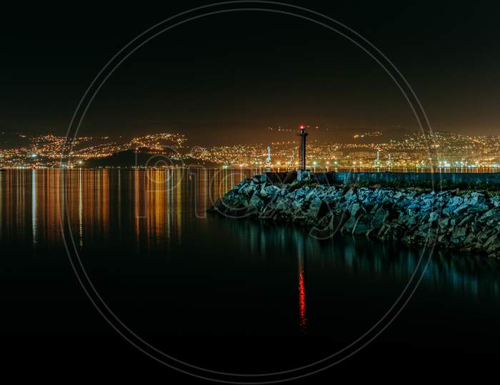 An Horizontal Colorful Shot Of The Lighthouse During The Night With The City Skyline During As The Background