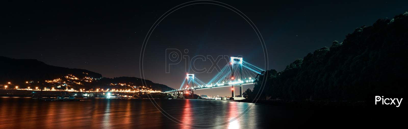 A Super Panoramic View Of A Full Of Lights Bridge During Night