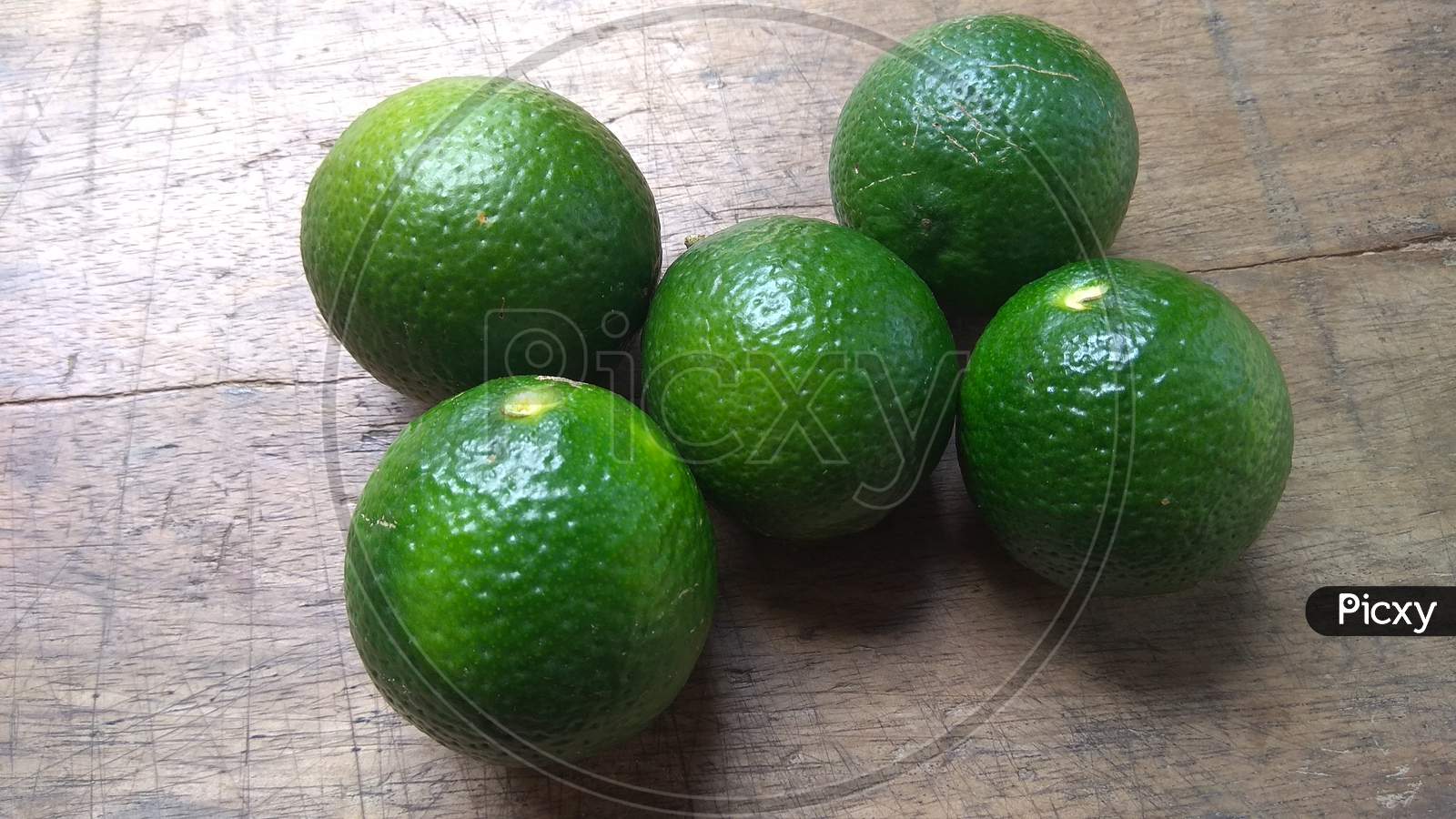 Fresh green lemons on wooden background.