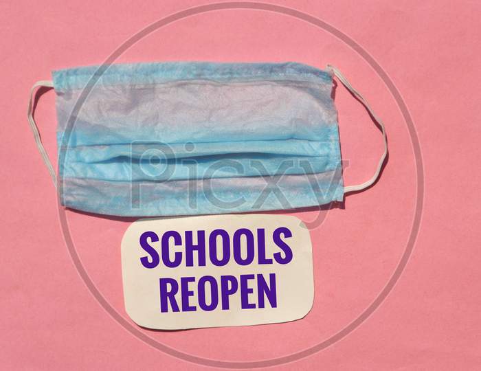 Schools Reopen Phrase With Medical Or Surgical Mask Isolated On Pink Background