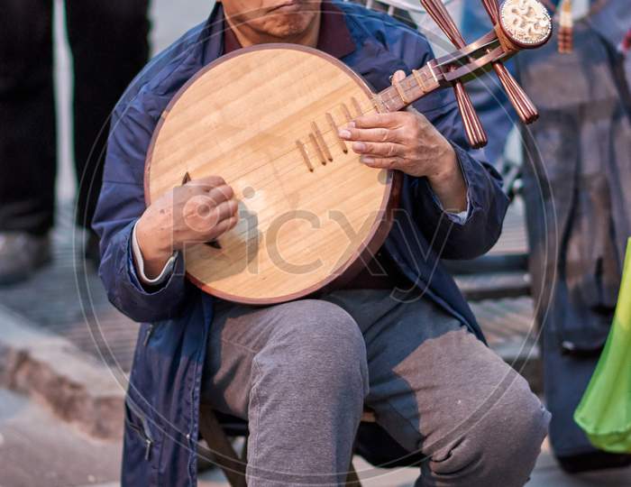 Elderly Man Playing Traditional Chinese Instrument In A Park In Beijing, China