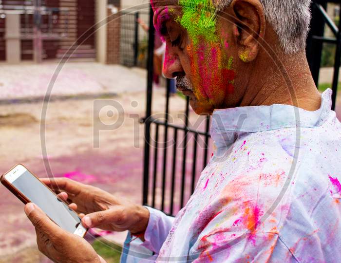 Old Man Using Mobile Phone During Holi