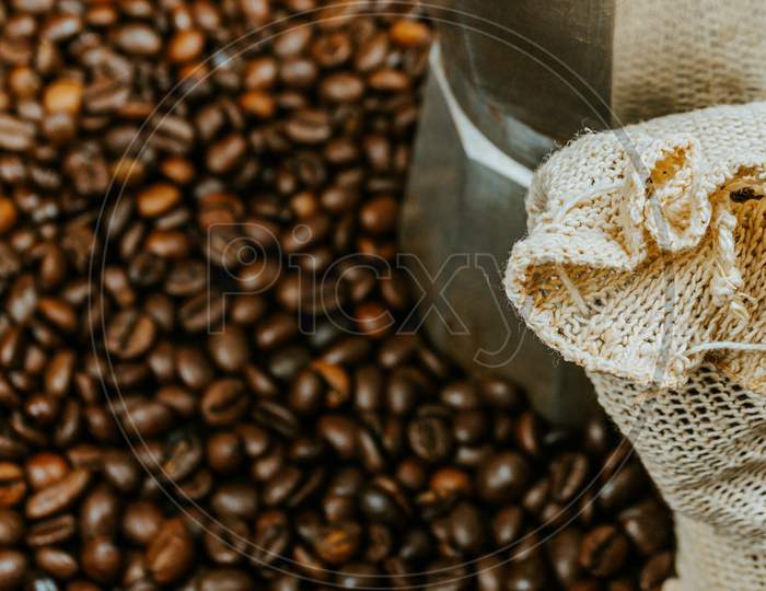A Close Up Of A Lot Of Coffee Grains Surrounding A Pot And A Coat