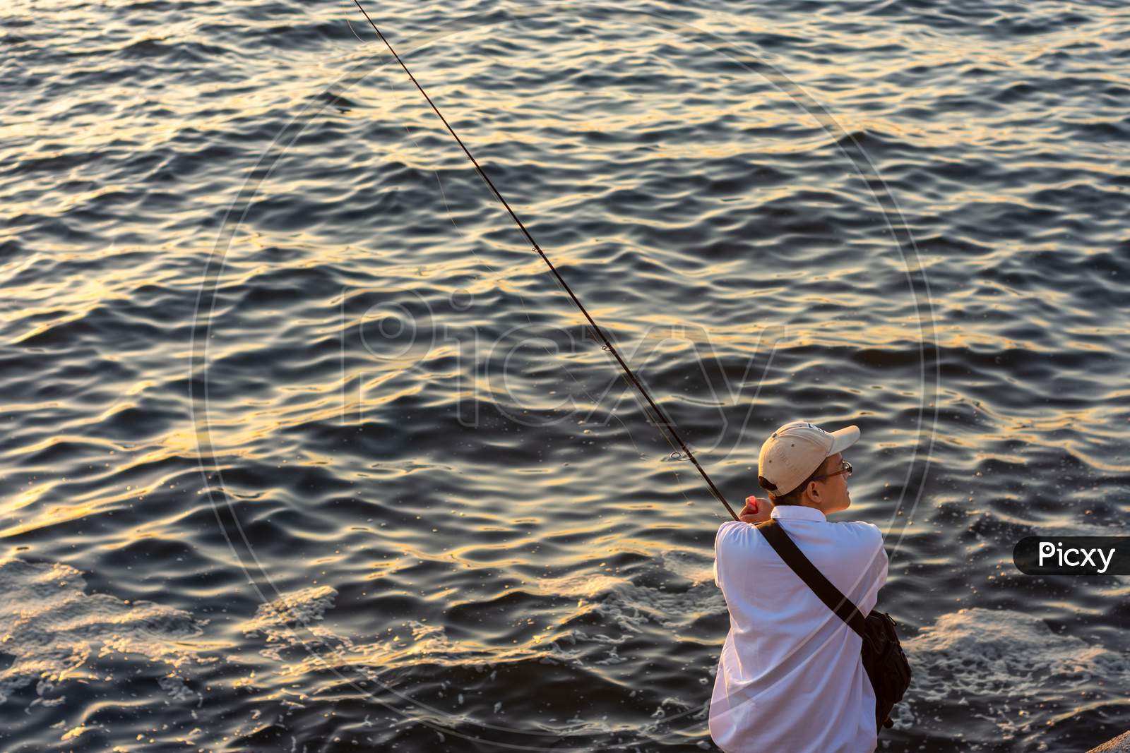 Japanese Man With A Fishing Rod Fishing At Seashore In Osaka Bay, Japan