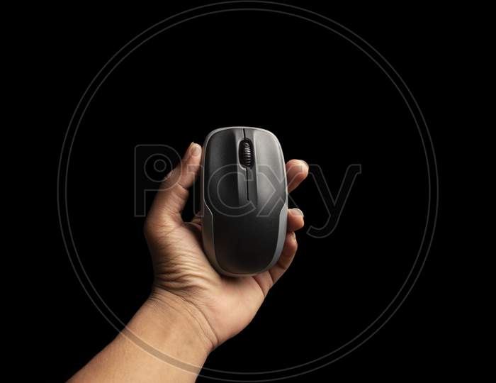 Hand Holding Computer Mouse Isolated On The Black Background. Above View Of Computer Mouse On Black Background. Black And Grey Computer Mouse.