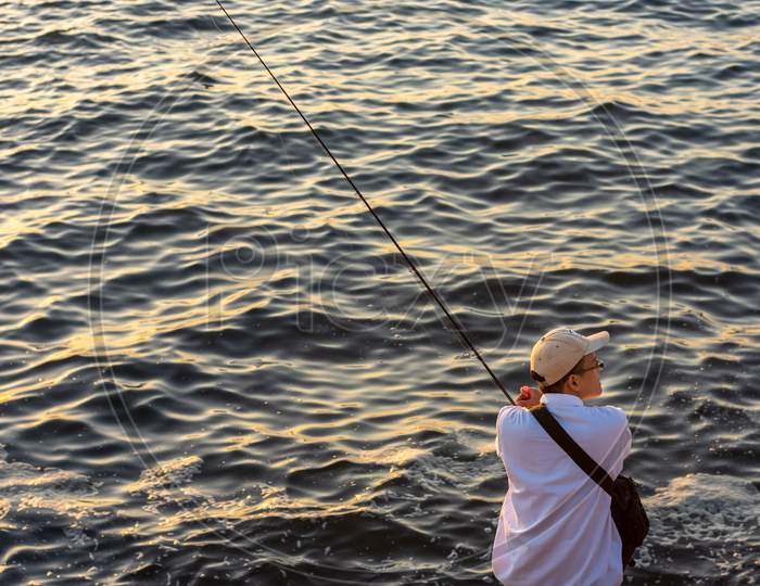 Japanese Man With A Fishing Rod Fishing At Seashore In Osaka Bay, Japan