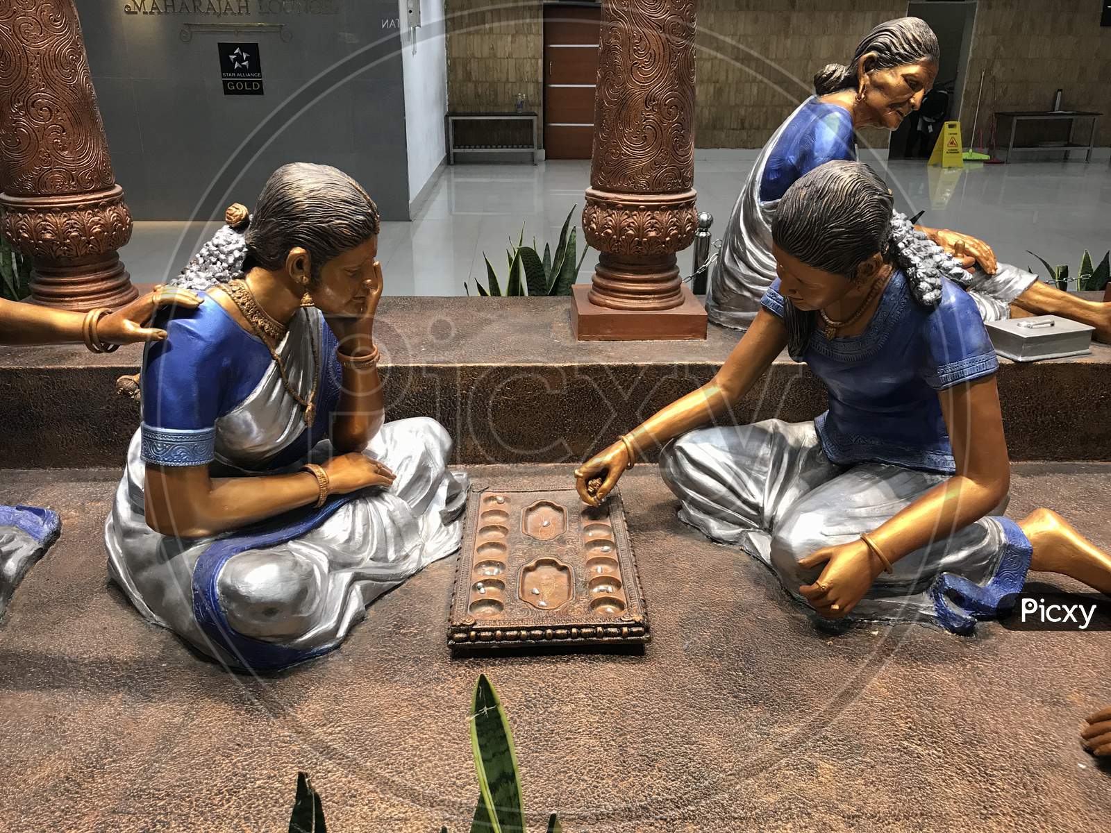 Statue Of Two Ladies Playing Ancient Tamil Games And Grandmother Statue Doing House Chores And Beautiful Status Are Located In Chennai India