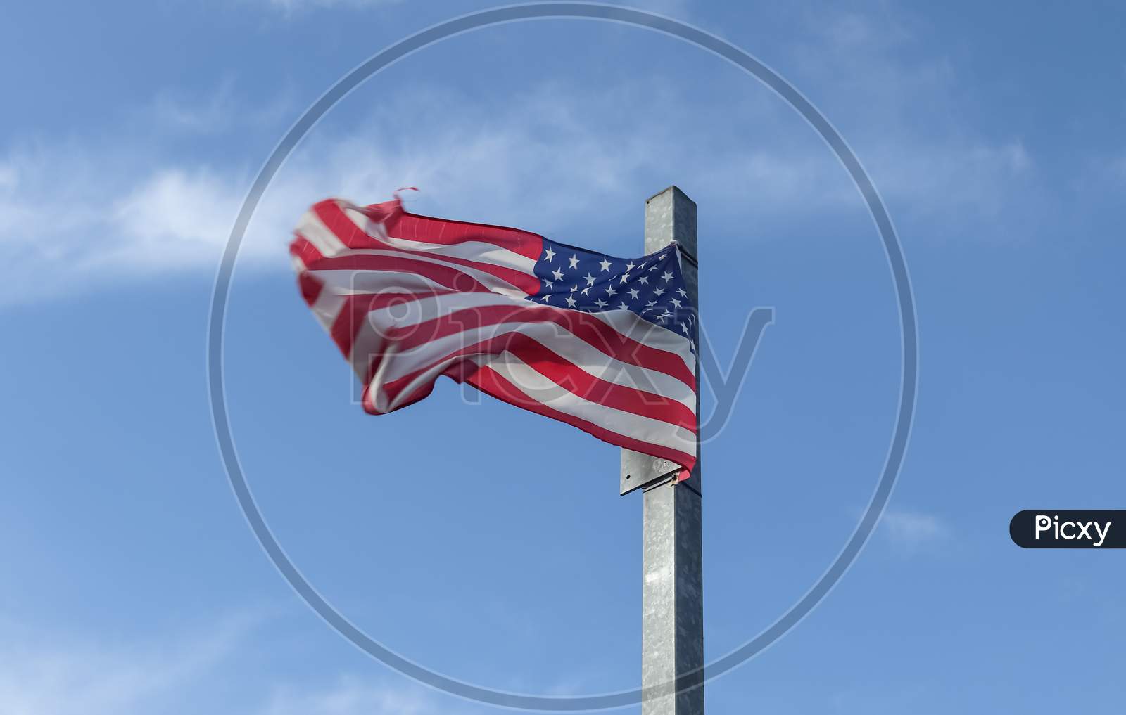 Usa Flag At A Flagpole Moving Slowly In The Wind Against The Sky