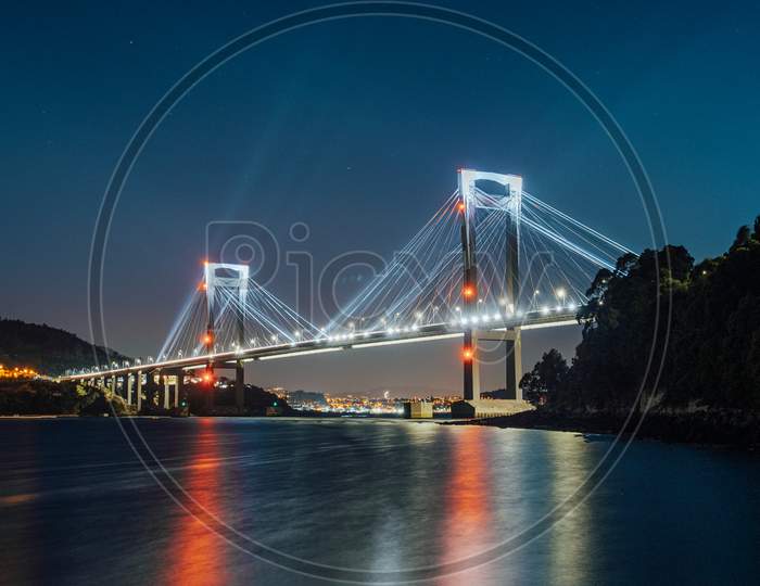 A Luminous Bridge Reflecting In The Water At Night