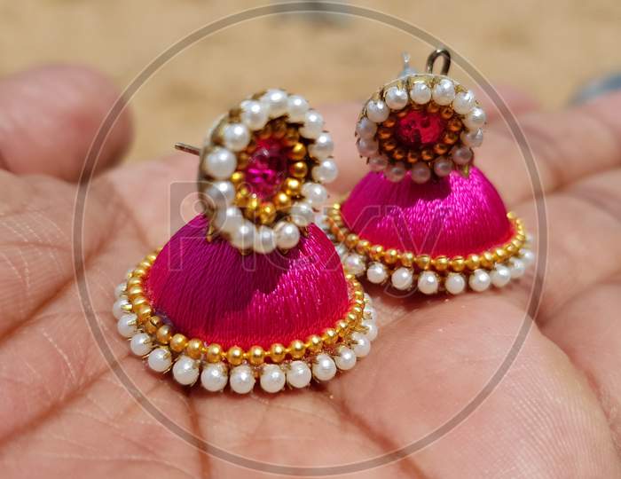 Holding Hand made colorful Earrings with blurred background