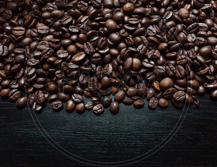 A Shot From Above Of A Lot Of Coffee Grains Over A Dark Wooden Background