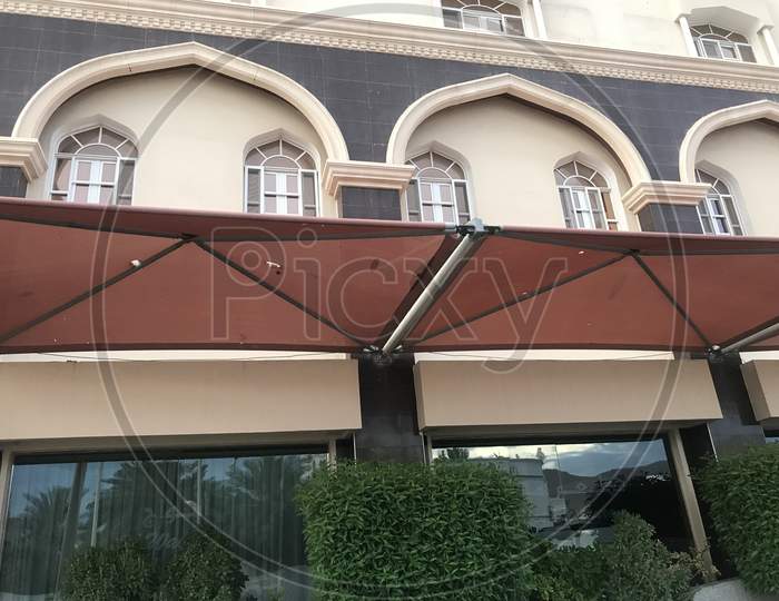 Brown Color Fabric Tensile Shade Structure In Front Of An Hotel Building For Shaded Area