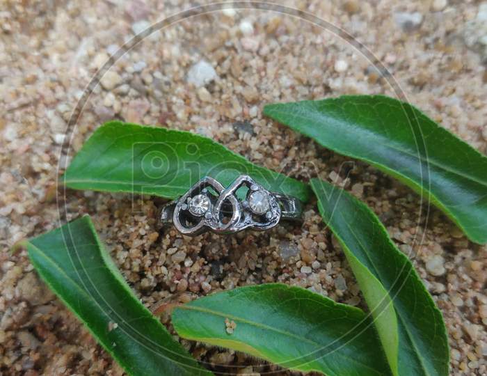 Wedding rings on the sand with rocks in a shape of a heart