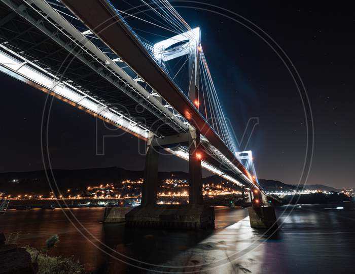 Luminous Bridge From Below Reflecting In The Water At Night