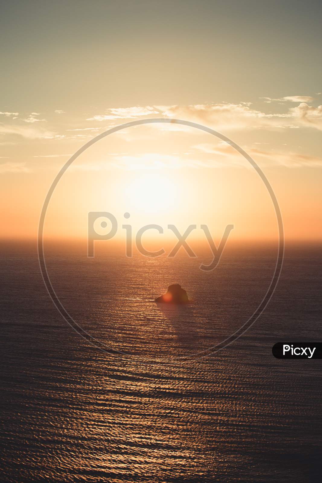 A Massive Sunset Over A Lonely Rock In The Middle Of The Ocean