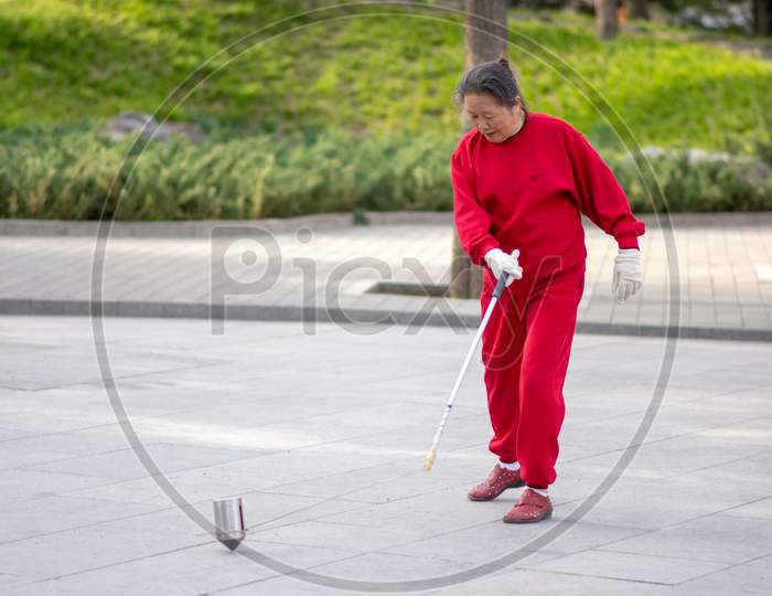 Old Chinese Woman Whipping Spinning Tops, Traditional Chinese Game, Beijing, China