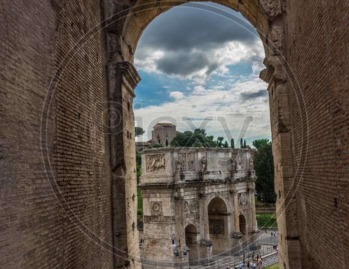 Rome, Italy - 23 June 2018: Arch Of Constantine Of The Roman Forum Viewed Through The Gated Arch Of The Passage At The Entrance Of The Roman Colosseum (Coliseum, Colosseo), Also Known As The Flavian Amphitheatre.