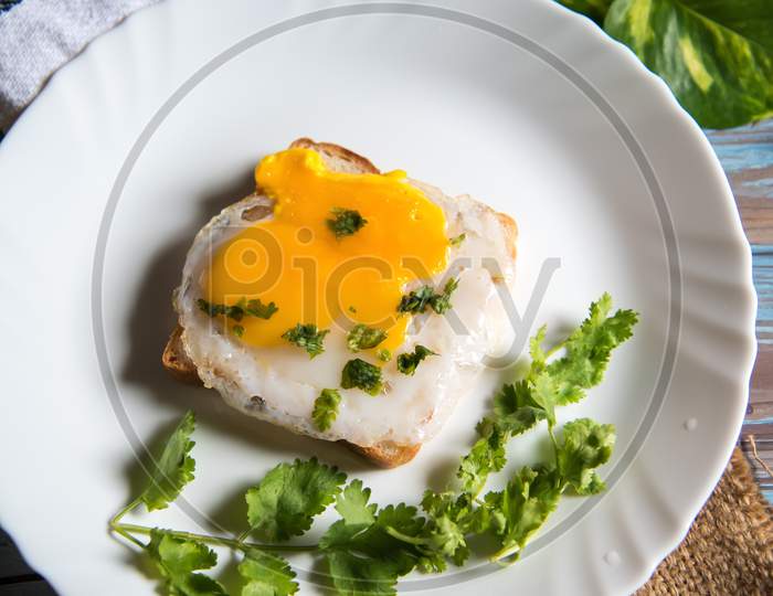 Poached egg on bread slice with condiments on a white plate