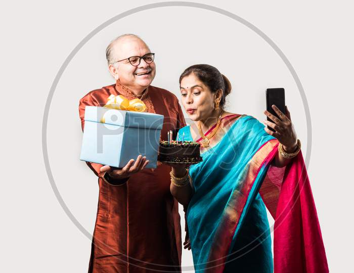 Indian Smart Old Couple Celebrating Birthday With Cake And Gifts