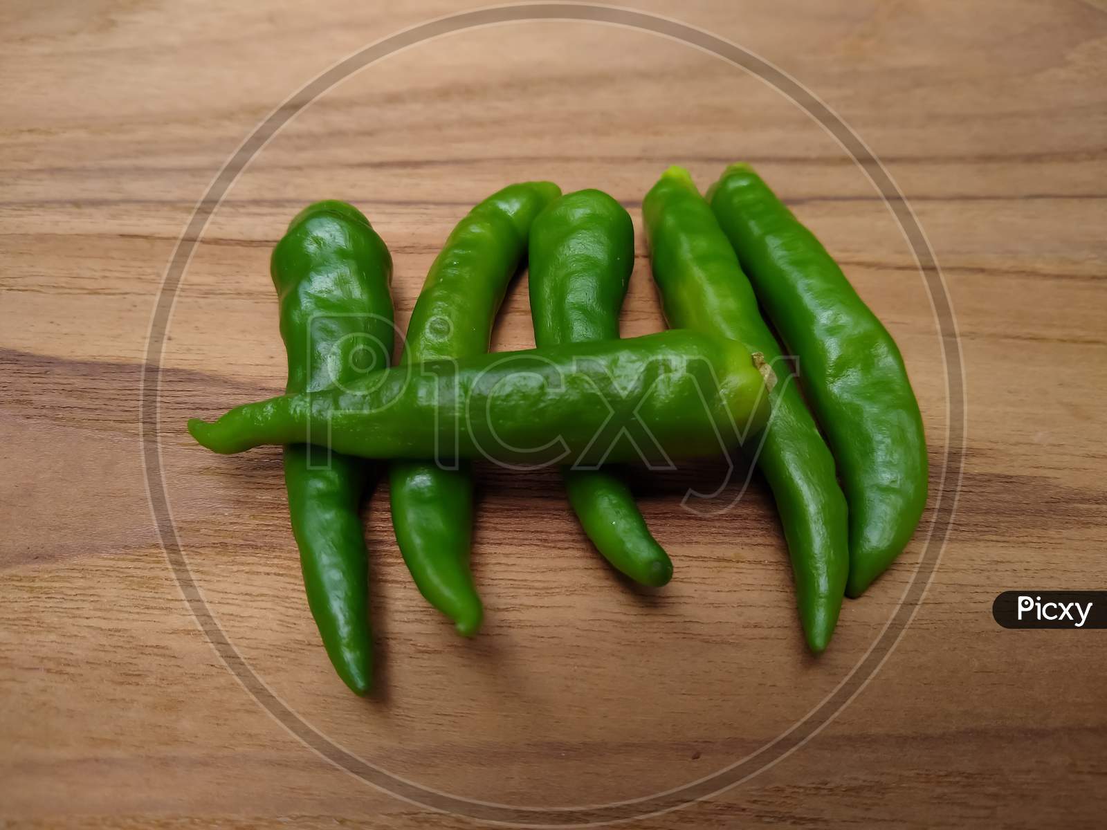 Green chilli peppers on wooden background