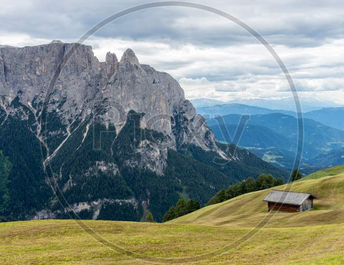 Alpe Di Siusi, Seiser Alm With Sassolungo Langkofel Dolomite, A Large Green Field With A Mountain In The Background