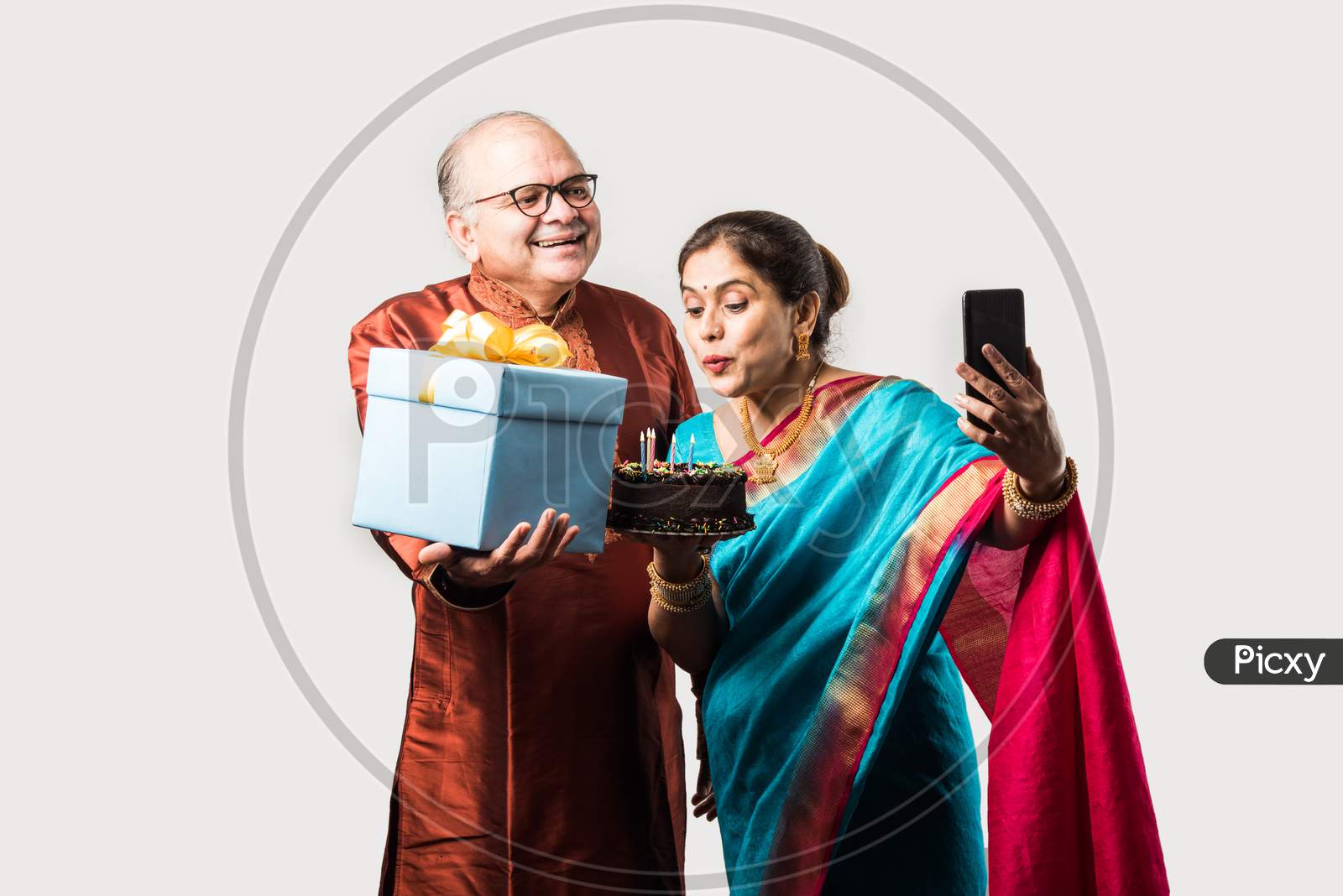 Indian Smart Old Couple Celebrating Birthday With Cake And Gifts