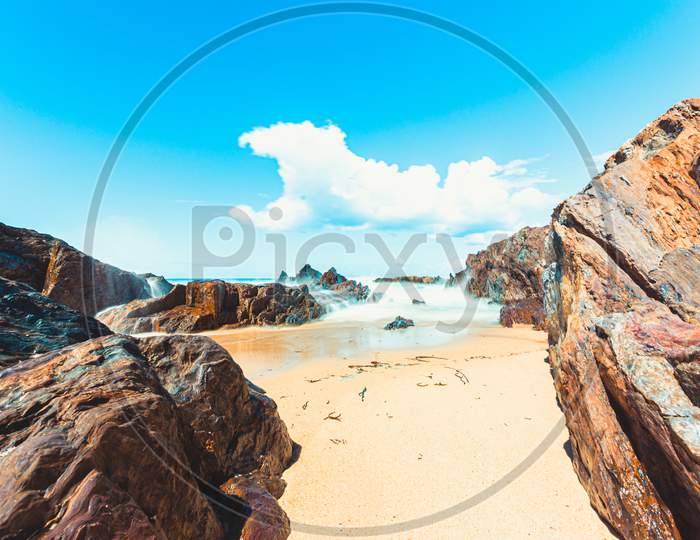 Long Exposure Shot Of A Beach Between The Rocks During A Bright Sunny Day