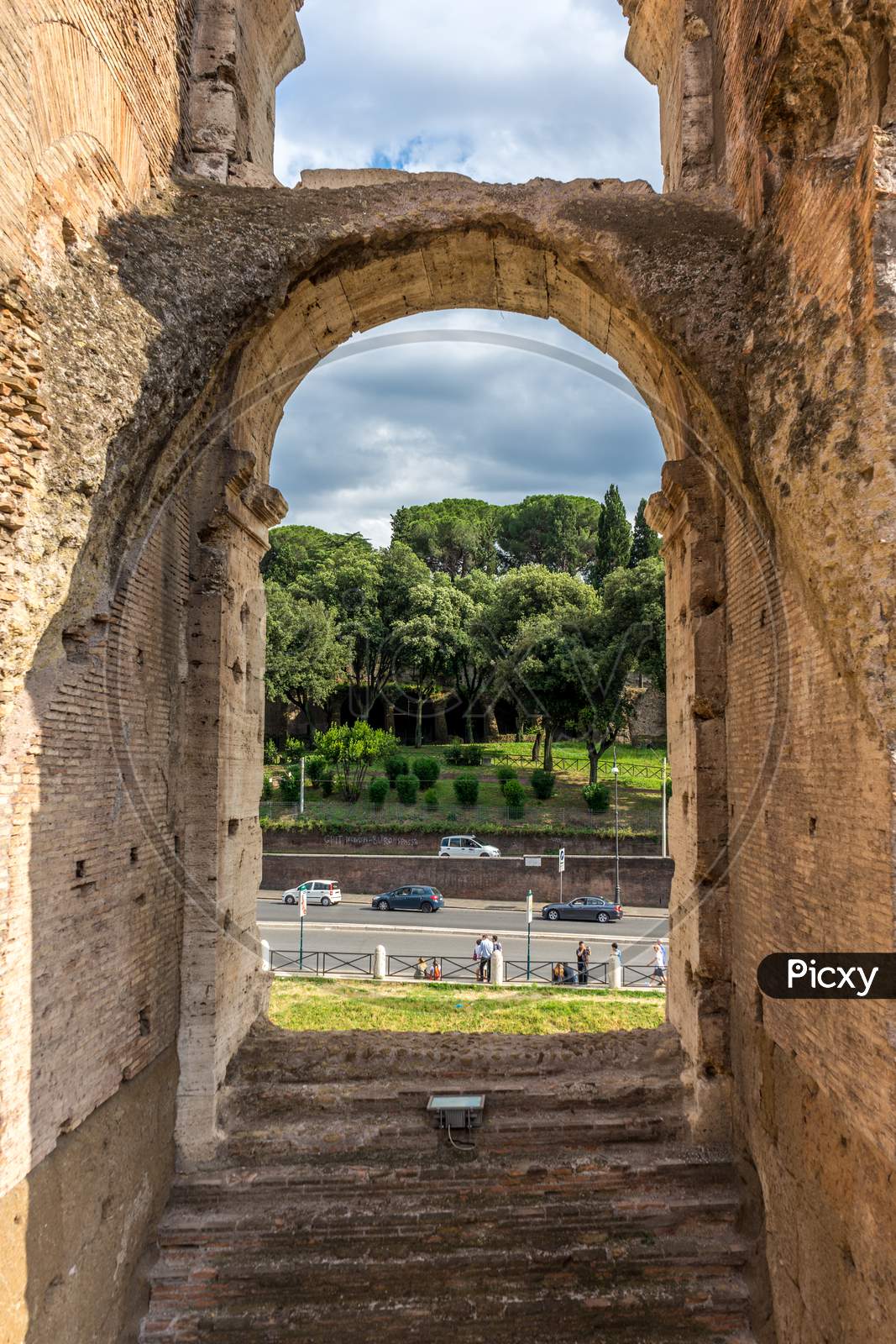 Rome, Italy - 23 June 2018: Ruins Of The Roman Forum Viewed Through The Gated Arch Of The Passage At The Entrance Of The Roman Colosseum (Coliseum, Colosseo), Also Known As The Flavian Amphitheatre.