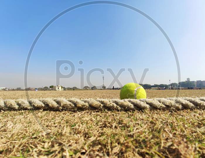 Close up Tennis Cricket ball on field touching boundary rope four runs