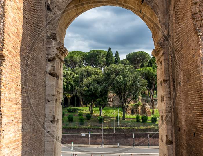 Rome, Italy - 23 June 2018: Ruins Of The Roman Forum Viewed Through The Gated Arch Of The Passage At The Entrance Of The Roman Colosseum (Coliseum, Colosseo), Also Known As The Flavian Amphitheatre.