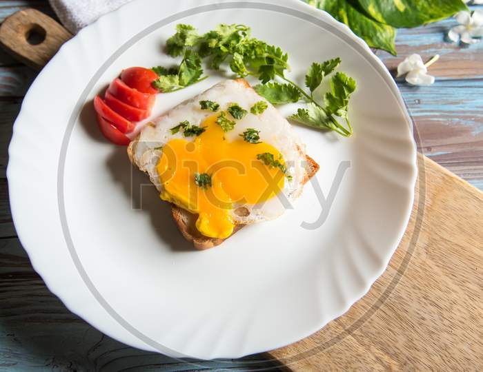Bread toast and egg poach with ingredients on a white plate on a wooden platter