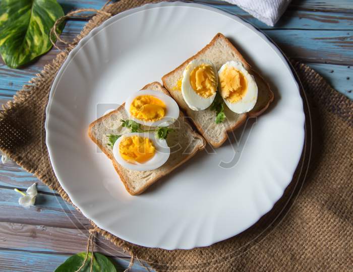 Vertical view of boiled eggs on slices of bread in a white plate