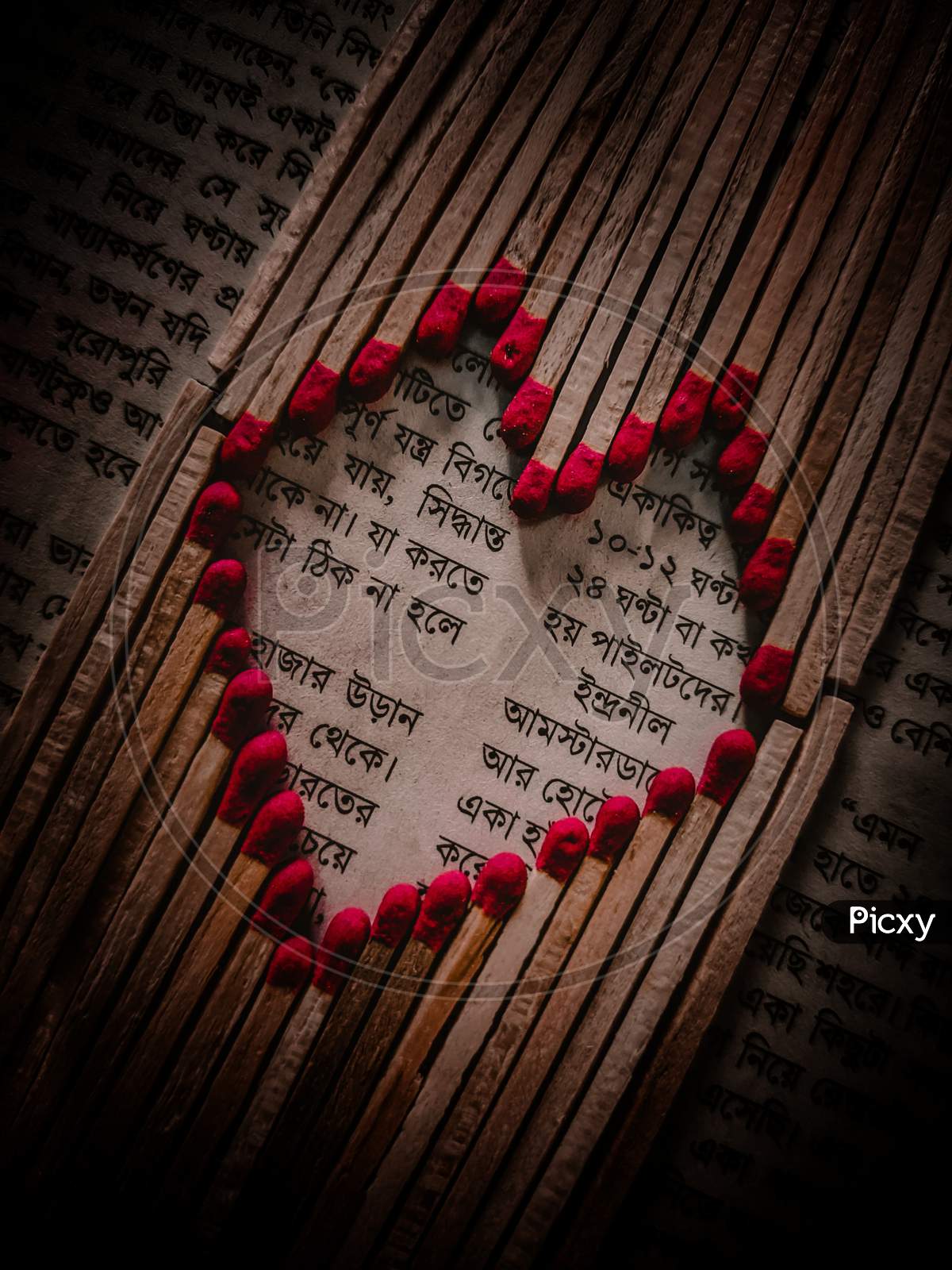 Heart shape made of matchstick on newspaper