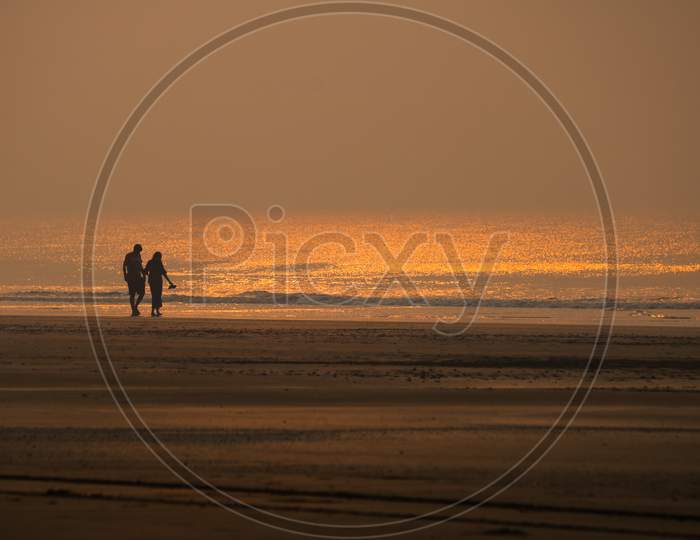 A couple is walking on the beach in the morning
