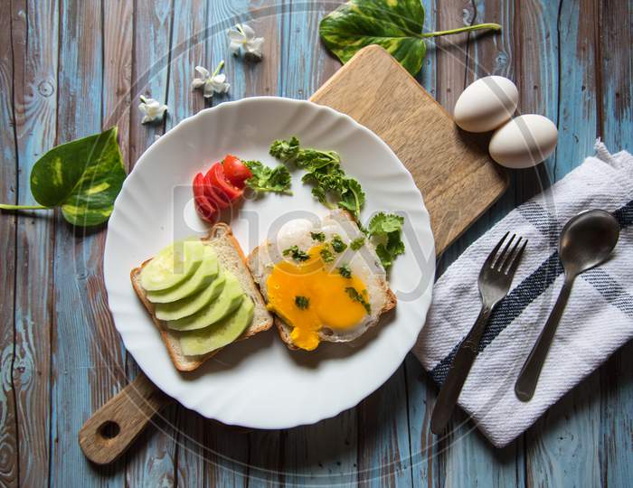 Cucumber and egg ingredients on bread toast in a plate on a wooden platter