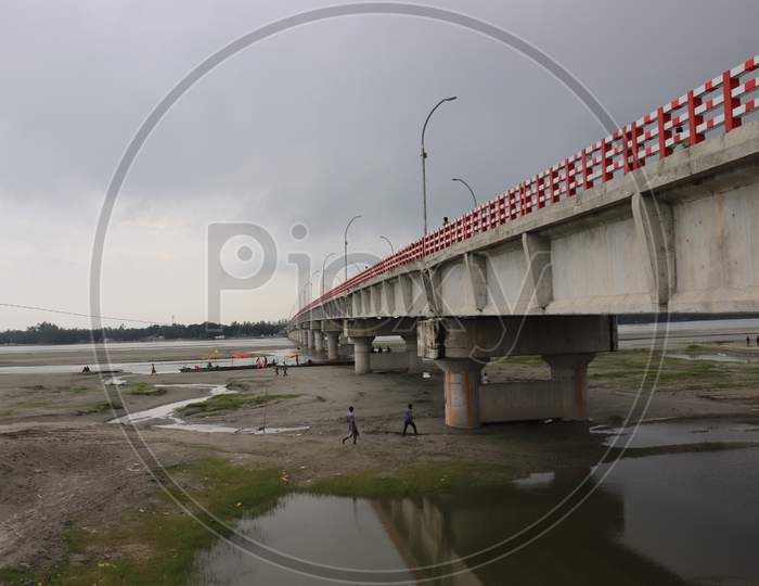 Long Big Concrete Bridge.An Elevated Concrete Highway Spanning Across A Dark Cloudy Sky.View Under The Grey Briage In The City.Modern Construction Engineering For Road.