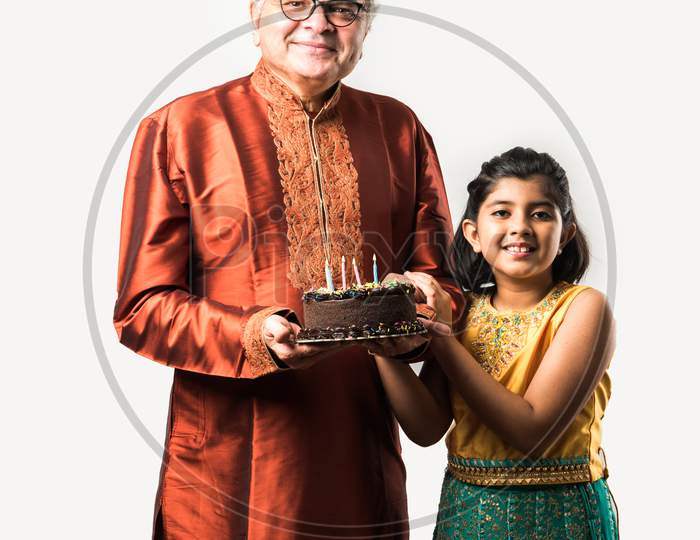 Indian Grandfather And Granddaughter Celebrating Birthday Together With Chocolate Cake