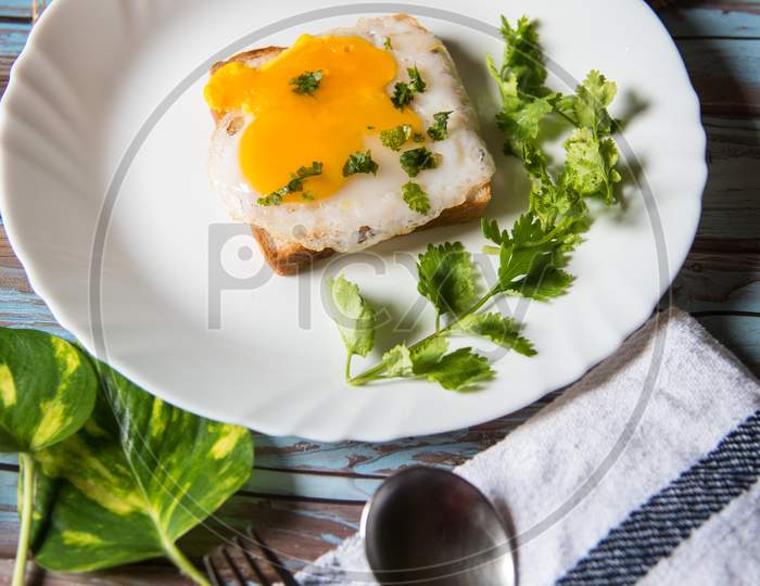 Top view of fried eggs with bacon and bread in a white plate