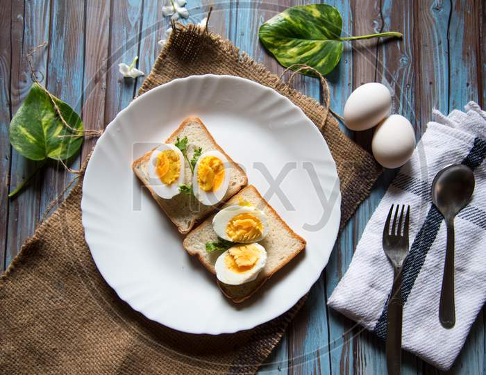 Top view of boiled eggs on bread slices in a plate with condiments