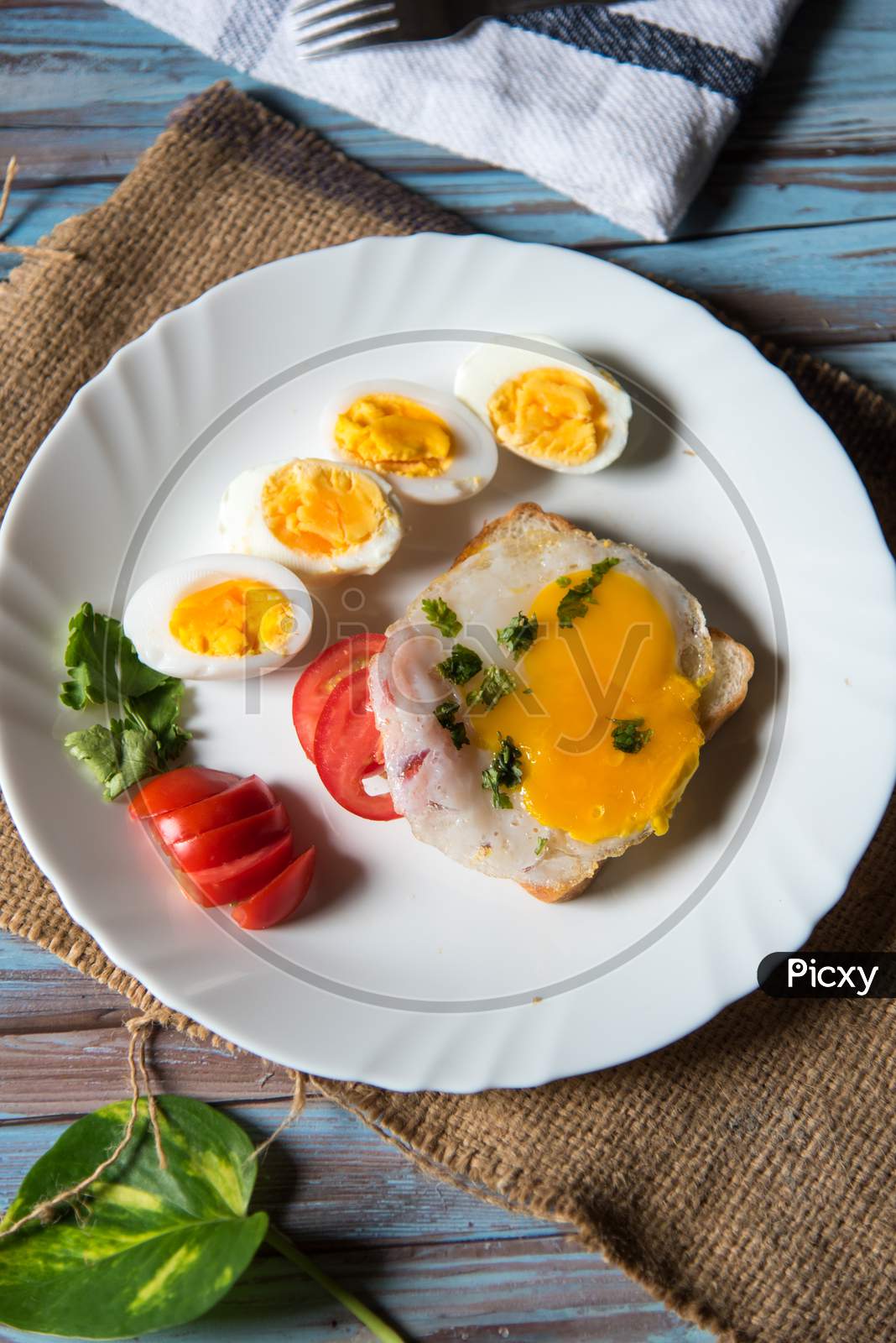 Vertical view of bread slice with poached egg and slices of boiled eggs