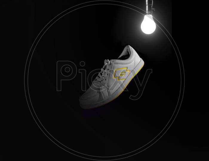 Black background white sneakers shoes with bulb