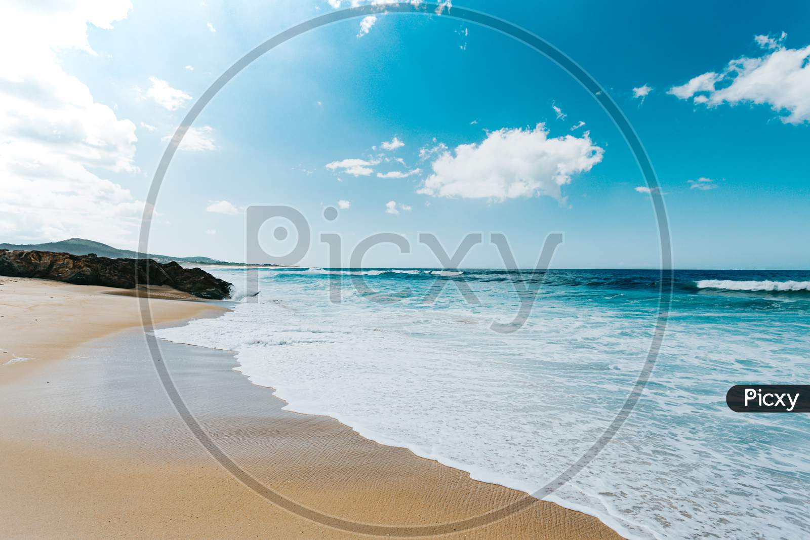 Massive Wild Beach With A Wave Of Sea Entering The Sand During A Sunny Day With A Super Bright Sky