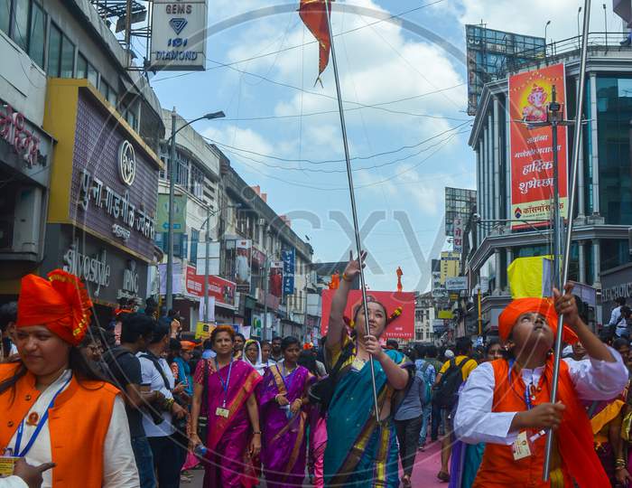 Pune, India - September 4, 2017: People Raising Orange Flags On The Occasion Of Ganpati Visarjan From Across India On The Streets Of Pune. Women And A Girl Happily Dancing With The Traditional Flags